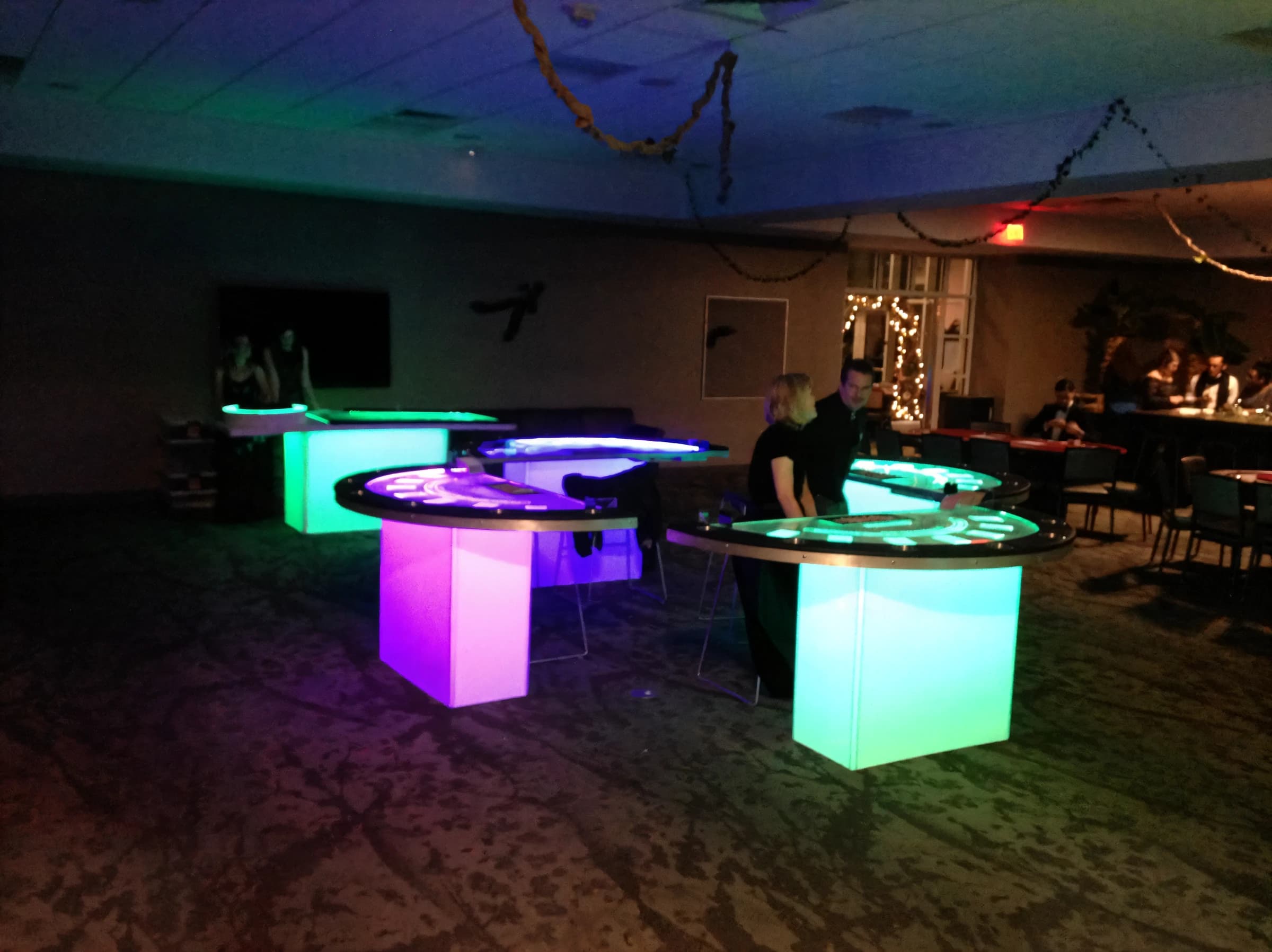Illuminated glow casino tables in pink, teal, and blue