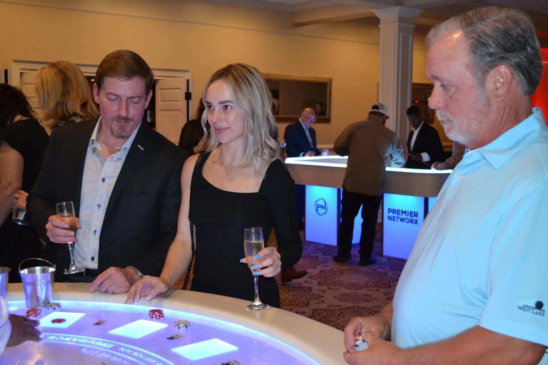 Guests playing at a sponsored glow blackjack table at a charity casino night