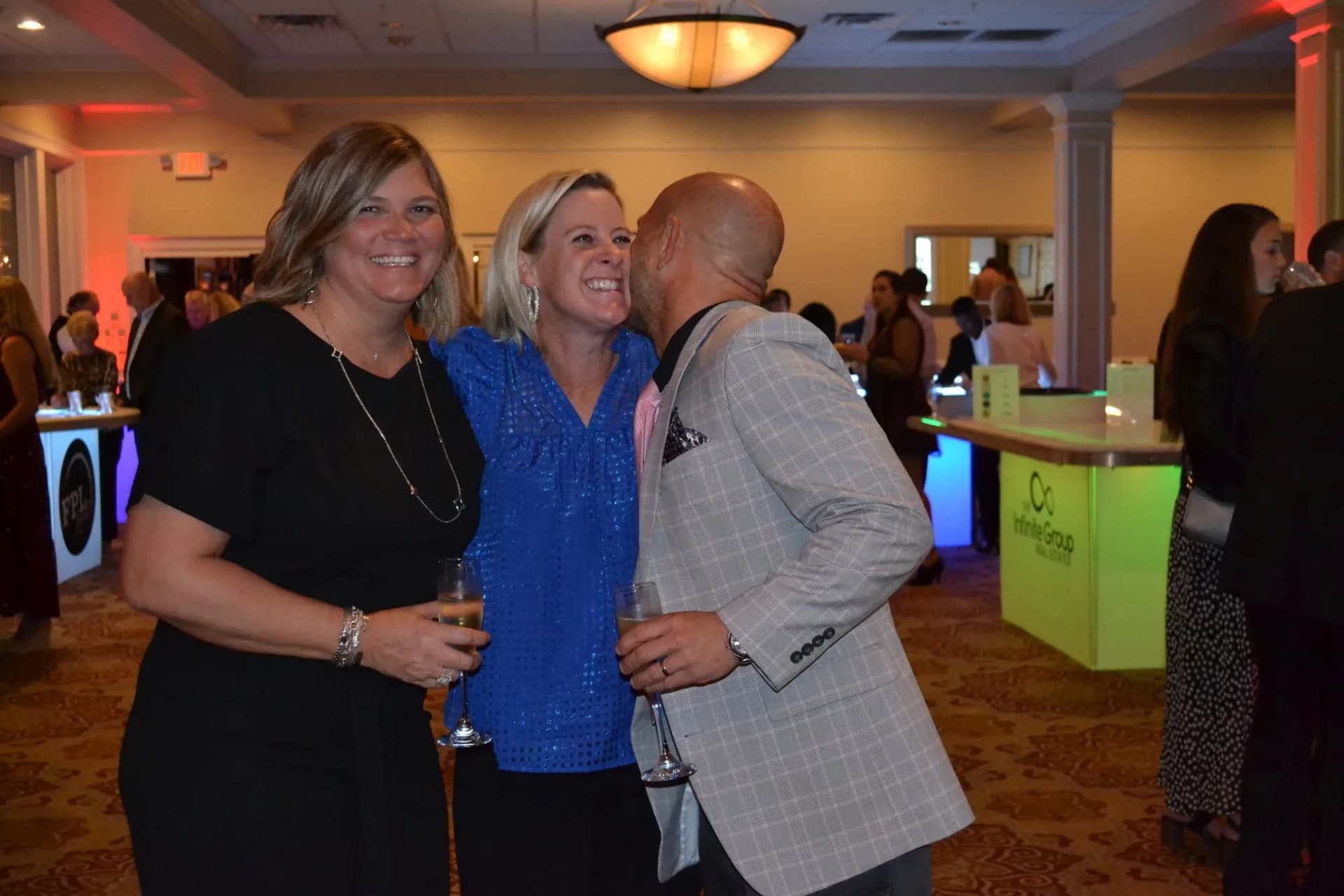 Guests celebrating beside sponsor-branded glow tables at a charity event