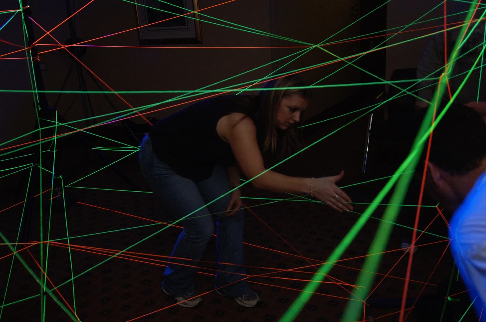 Participant navigating a glowing laser-web challenge at a team-building event