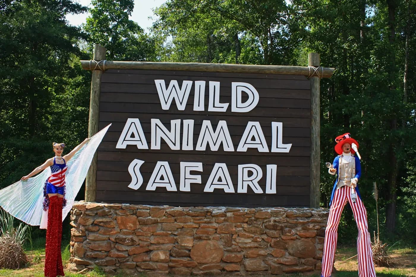 Stilt walkers in patriotic costumes at the Wild Animal Safari entrance sign