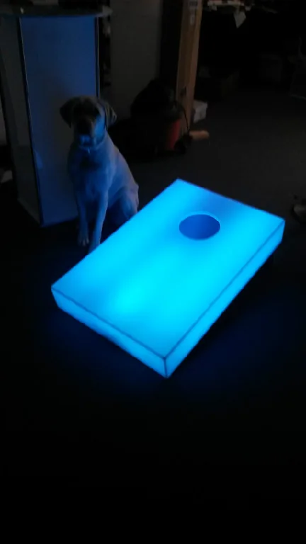Glow cornhole board lit blue at an indoor event
