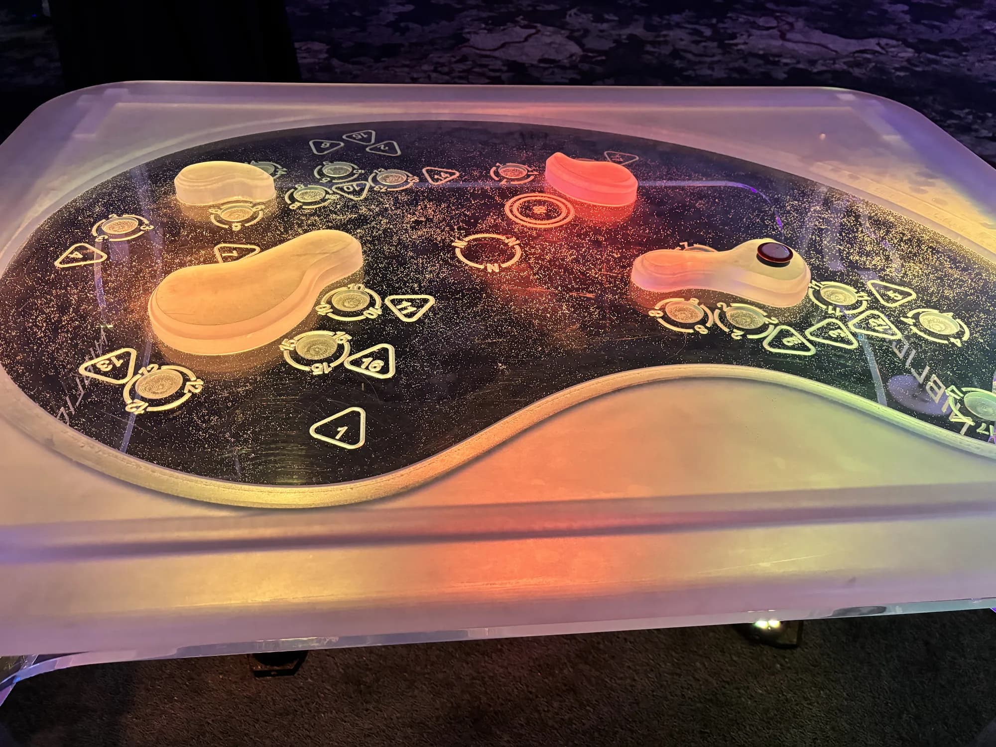 Glow game table lit orange and white with playing pieces, ready for guests
